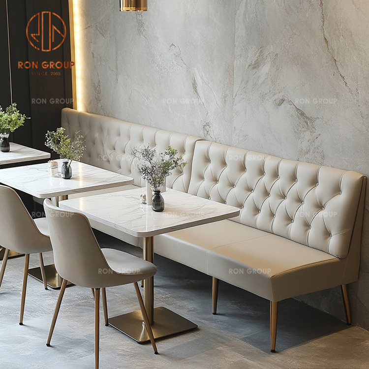Beige Button-Tufted Restaurant Booth Seating with Marble Tables and Upholstered Chairs